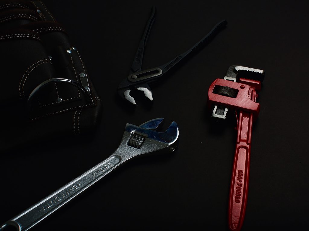 Plumber Tools Including Wrench and Pliers on Dark Background