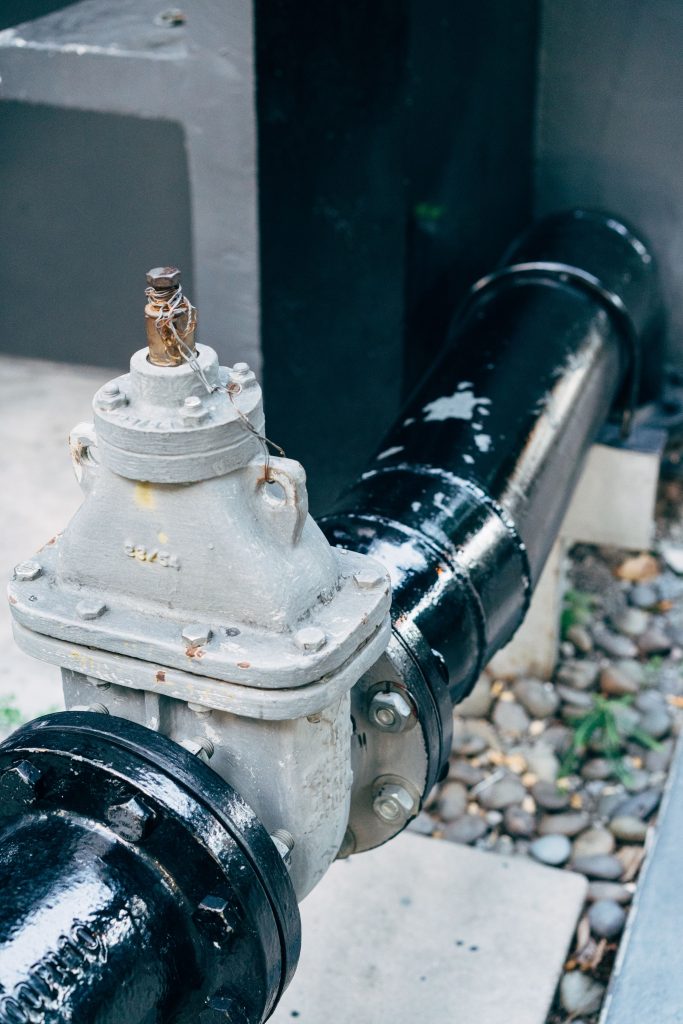 Industrial Plumbing Valve Connected to Black Pipe for Sewer Line Repair