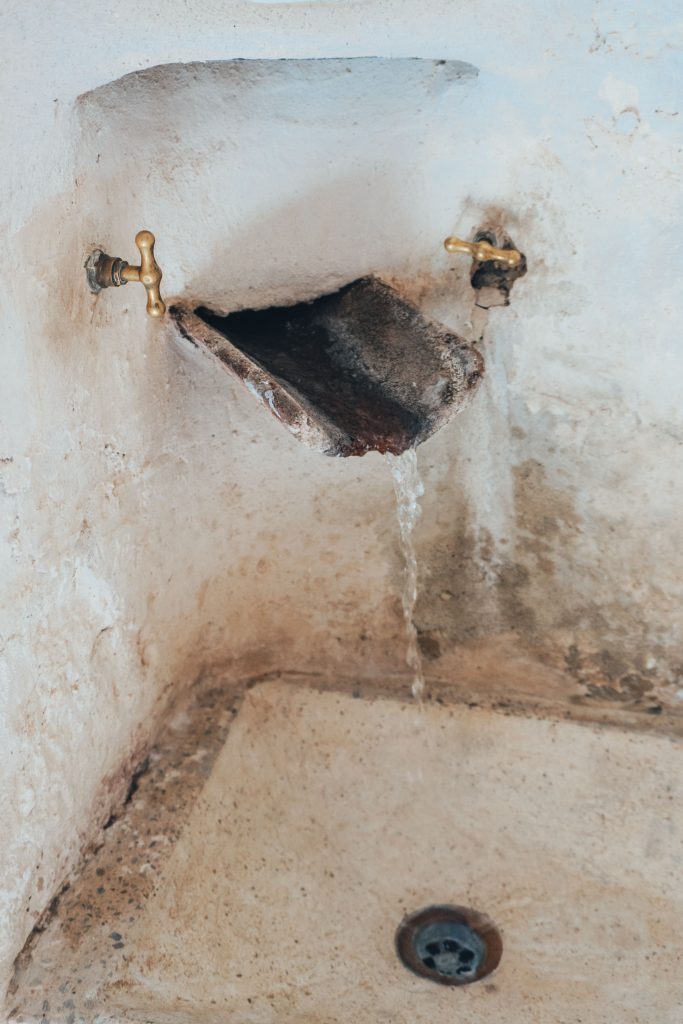 Rusty Sink Faucet with Water Flowing into a Drain