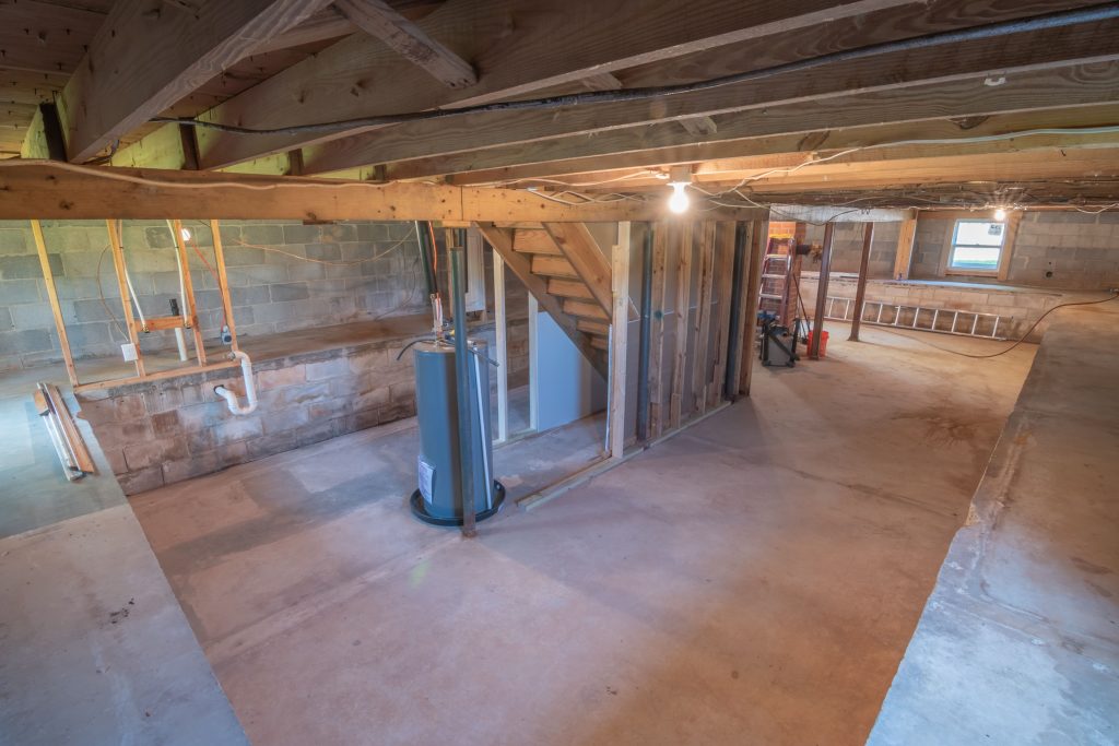 Unfinished Basement with Exposed Pipes and Water Heater in Need of Plumbing Service