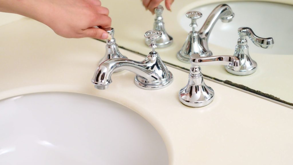 Hand Turning on Bathroom Faucet with Water Flowing, Plumbing Repair Near Me